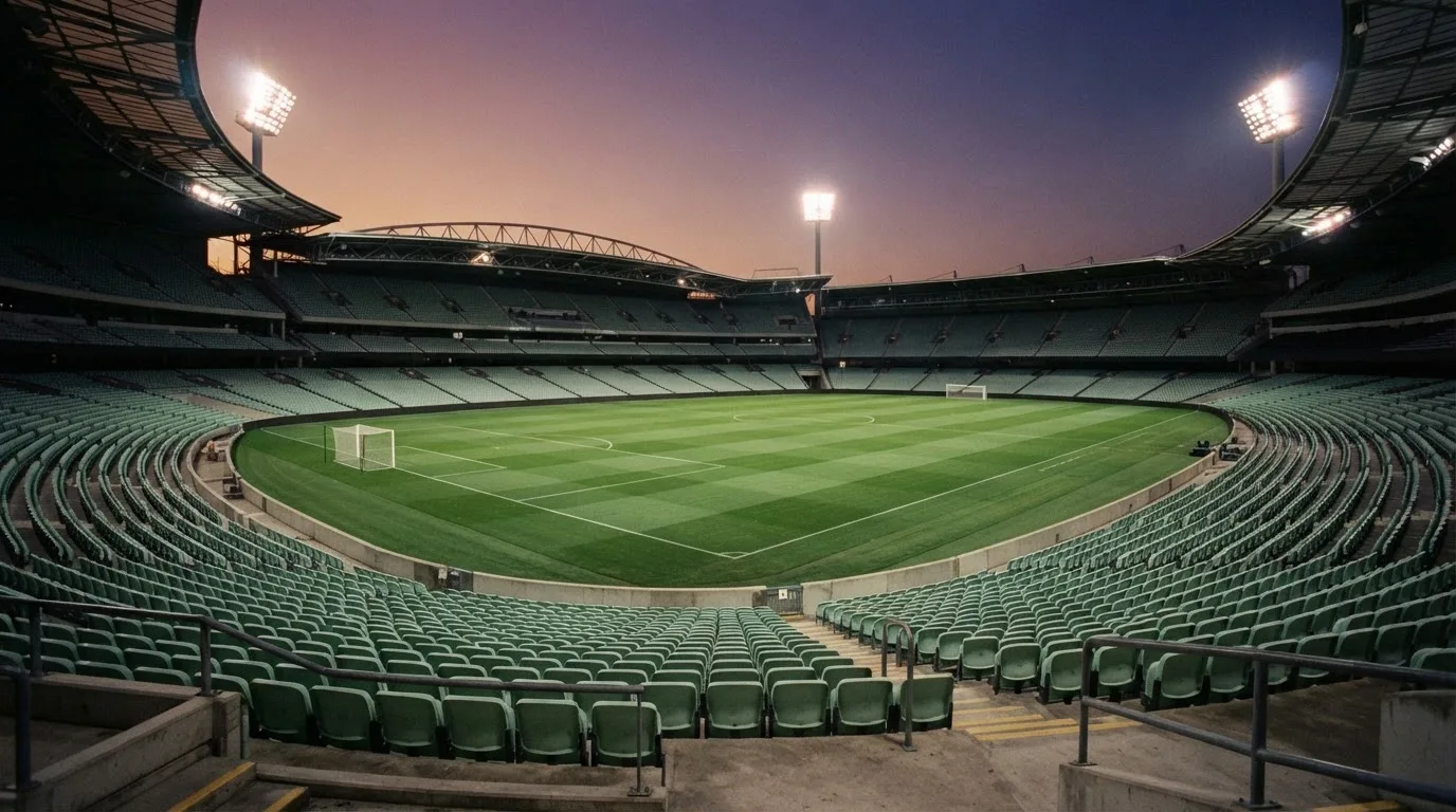 An empty football stadium with floodlight masts at dusk