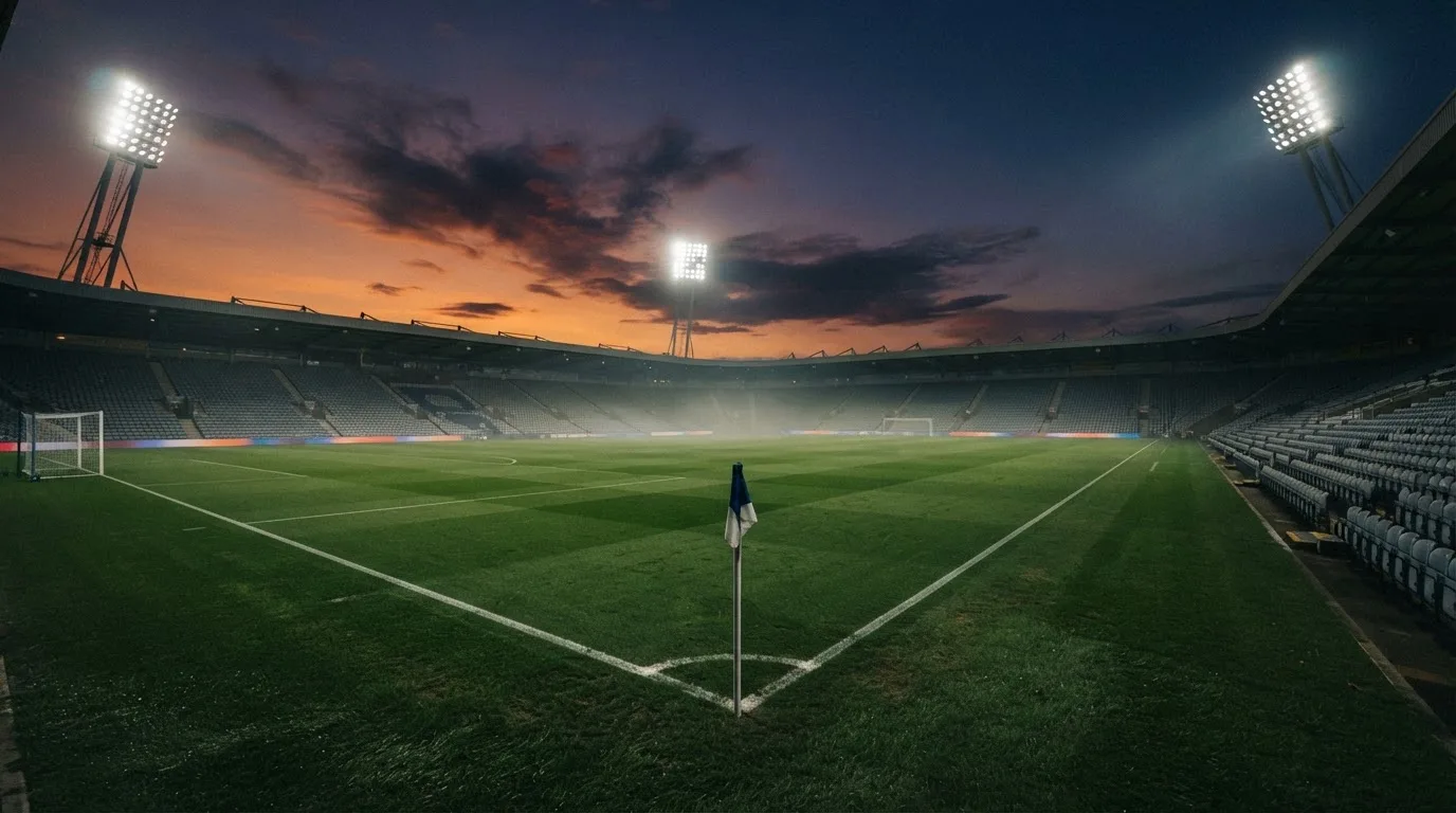 An empty football stadium with floodlight masts at dusk