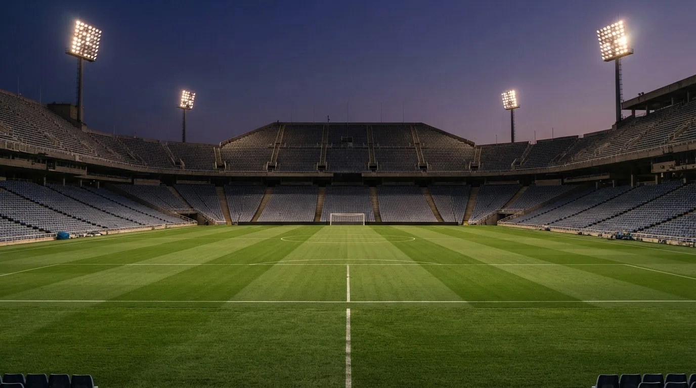 An empty football stadium with floodlight masts at dusk