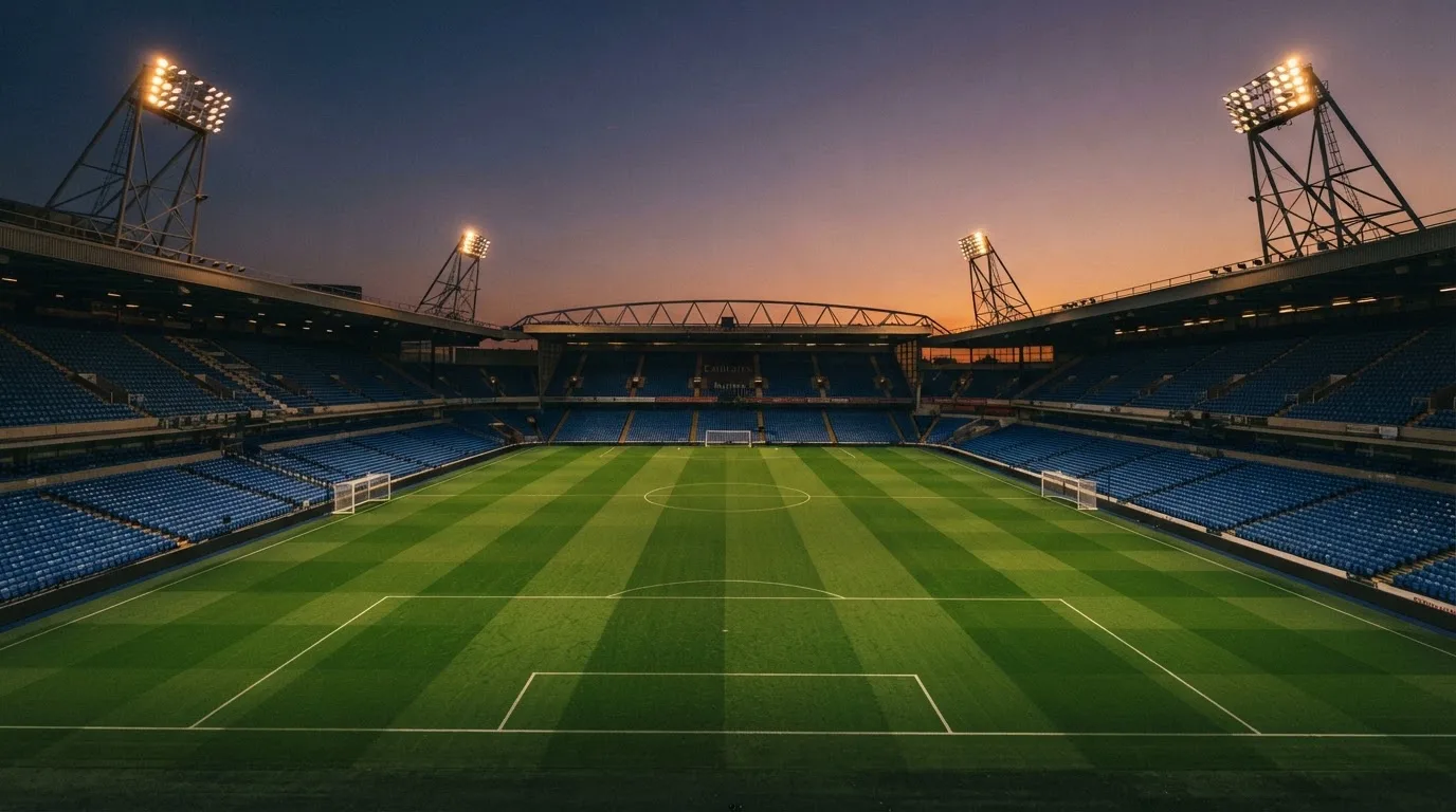 An empty football stadium with floodlight masts at dusk