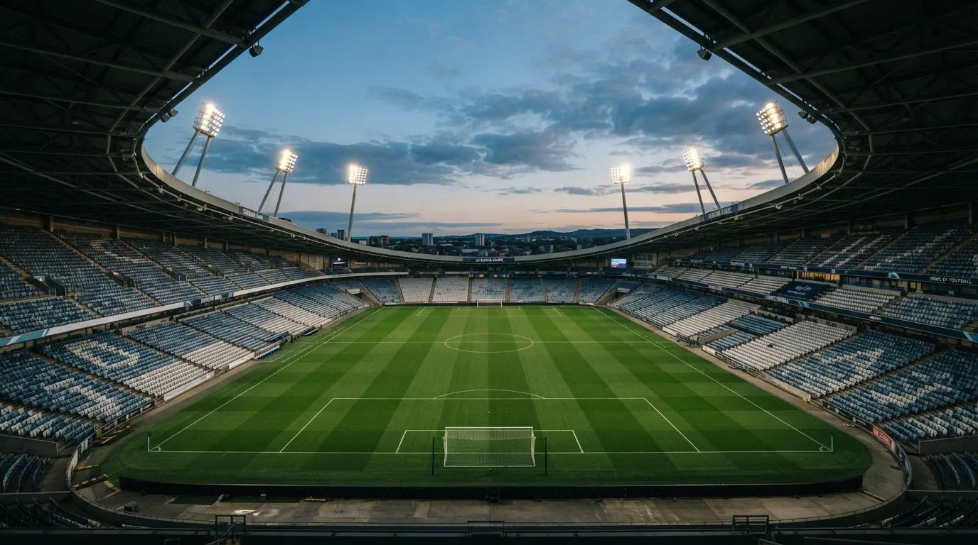 An empty football stadium with floodlight masts at dusk