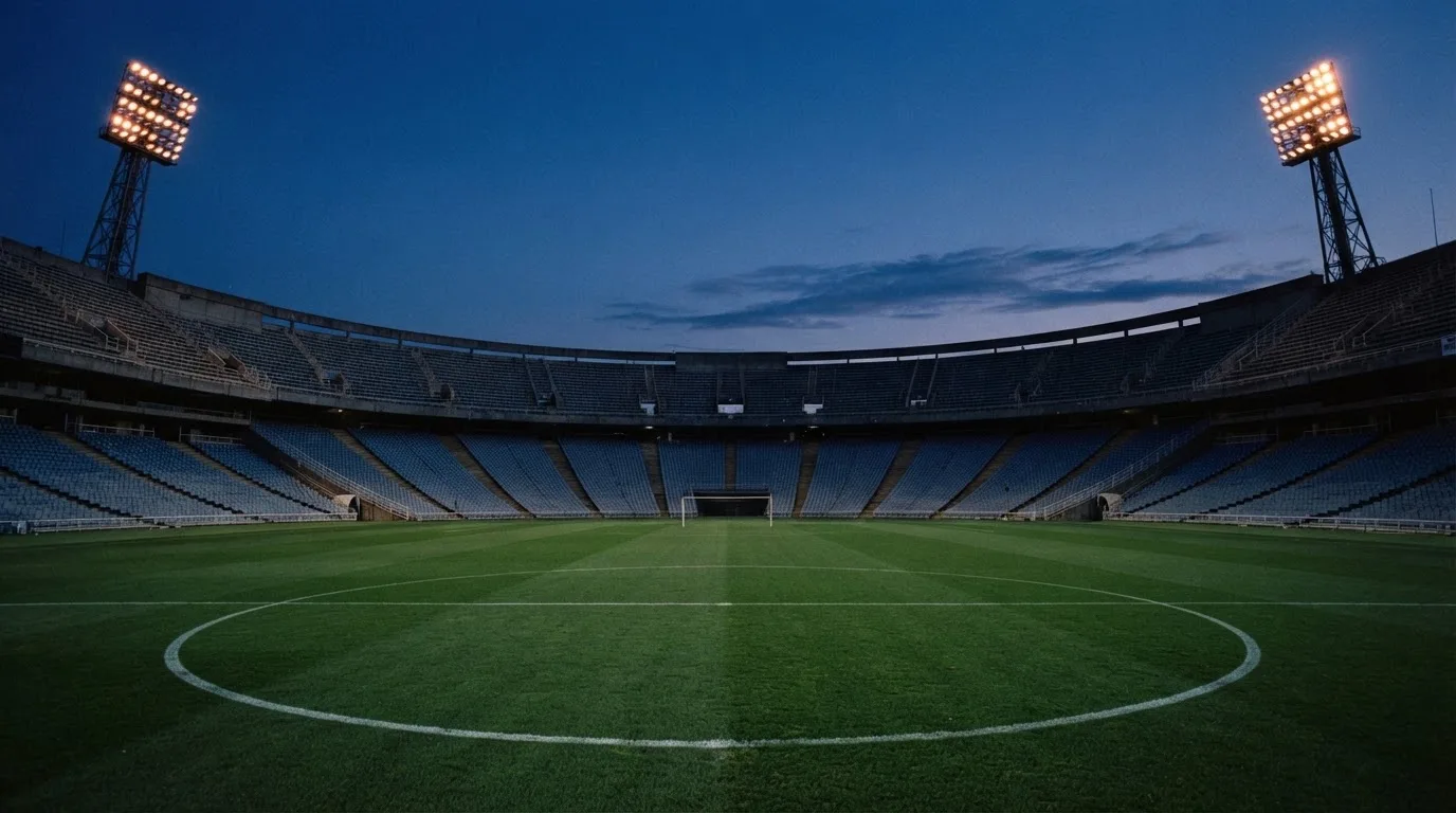 An empty football stadium with floodlight masts at dusk