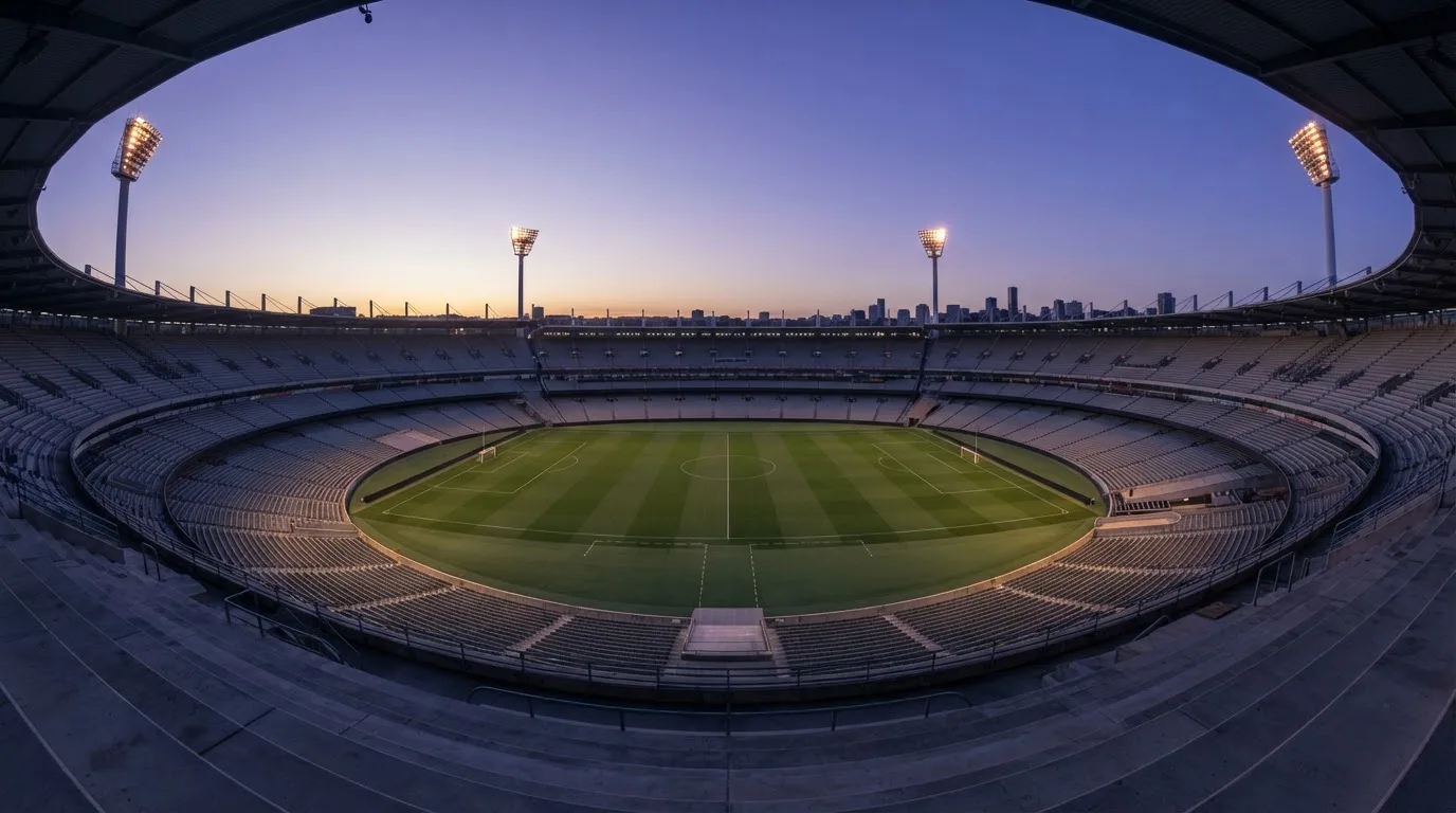 An empty football stadium with floodlight masts at dusk