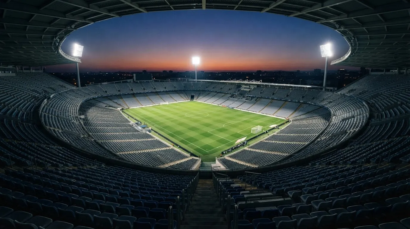 An empty football stadium with floodlight masts at dusk