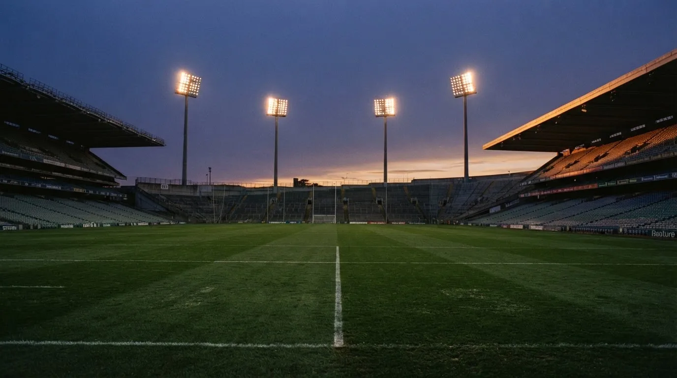 An empty football stadium with floodlight masts at dusk
