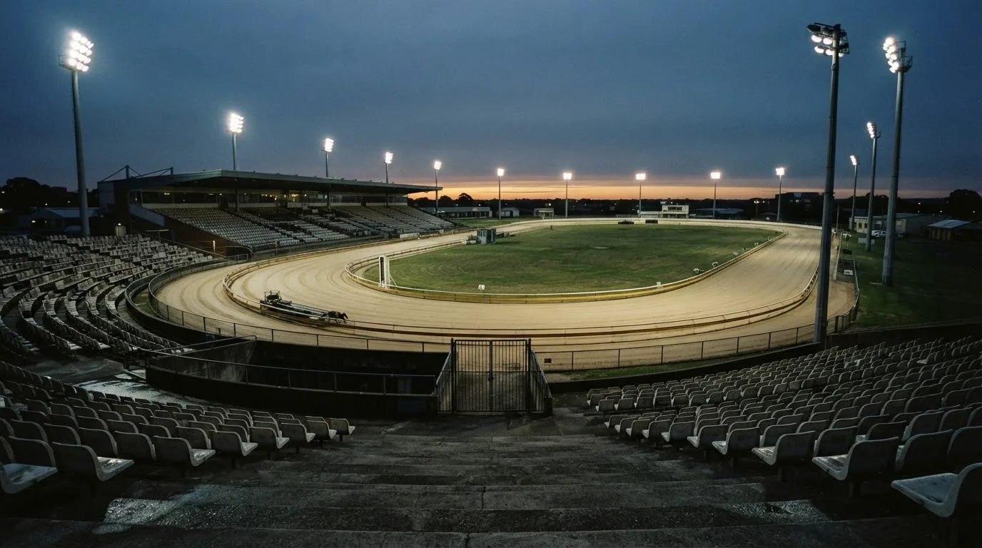 An empty football stadium with floodlight masts at dusk