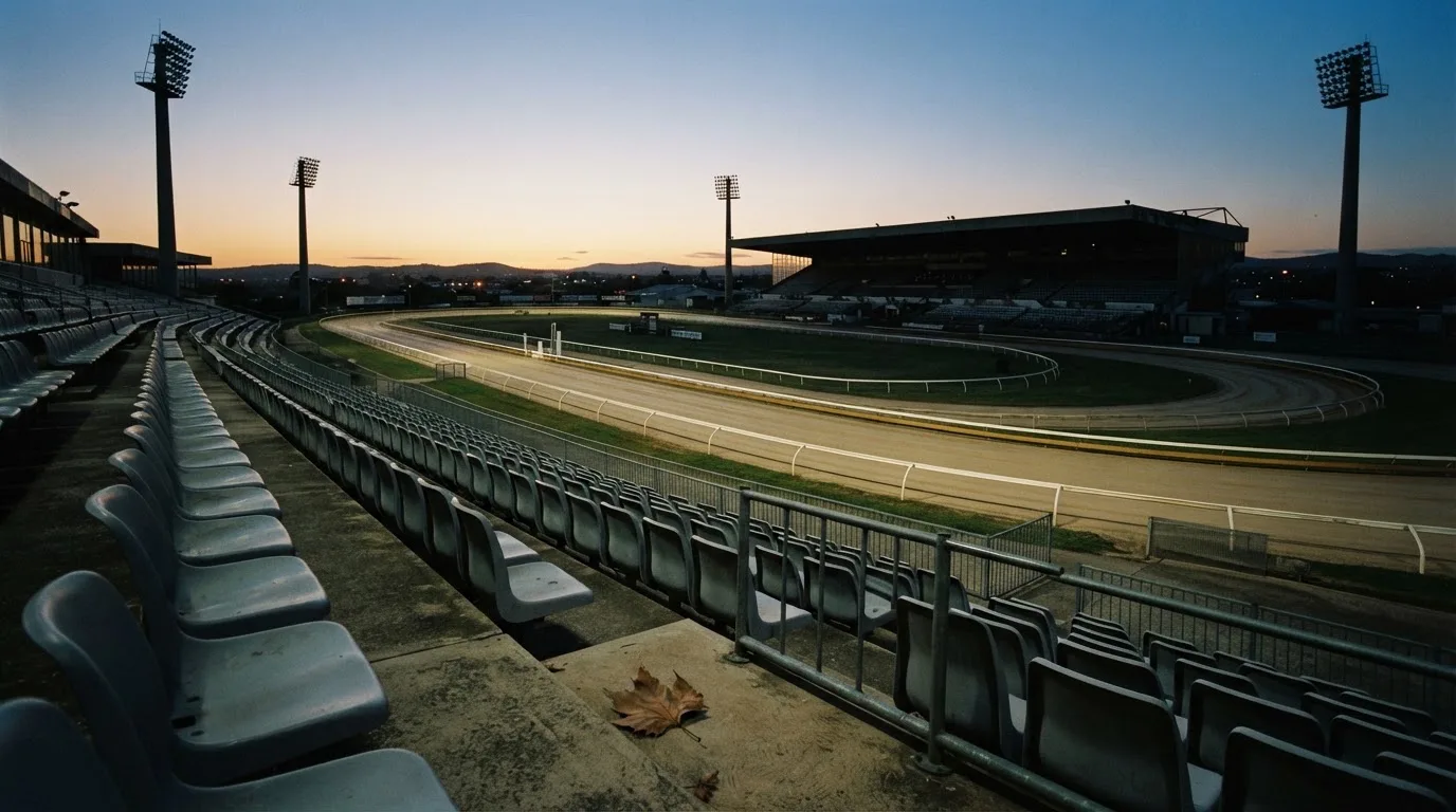 An empty football stadium with floodlight masts at dusk