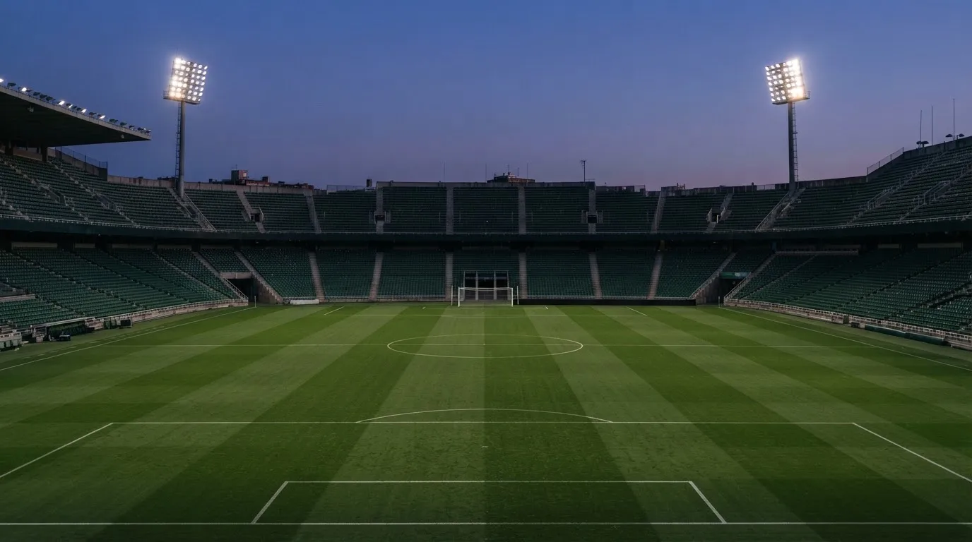 An empty football stadium with floodlight masts at dusk